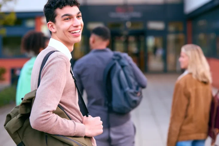 Jovem com uma mochila atrás de outros três jovens a ilustrar como preparar a ida para universidade longe de casa